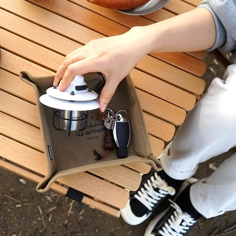 Khaki snap-tray holding a lantern and keys on a wooden surface