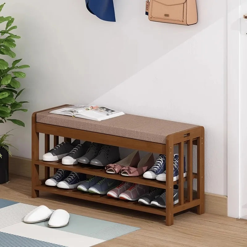 Entryway shoe storage bench with cushion holding several pairs of shoes in a hallway setting