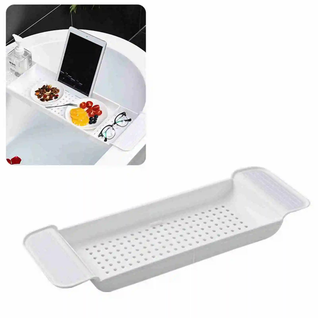 White expandable plastic bathtub tray with draining holes, shown placed across a bathtub holding snacks, a tablet, and glasses