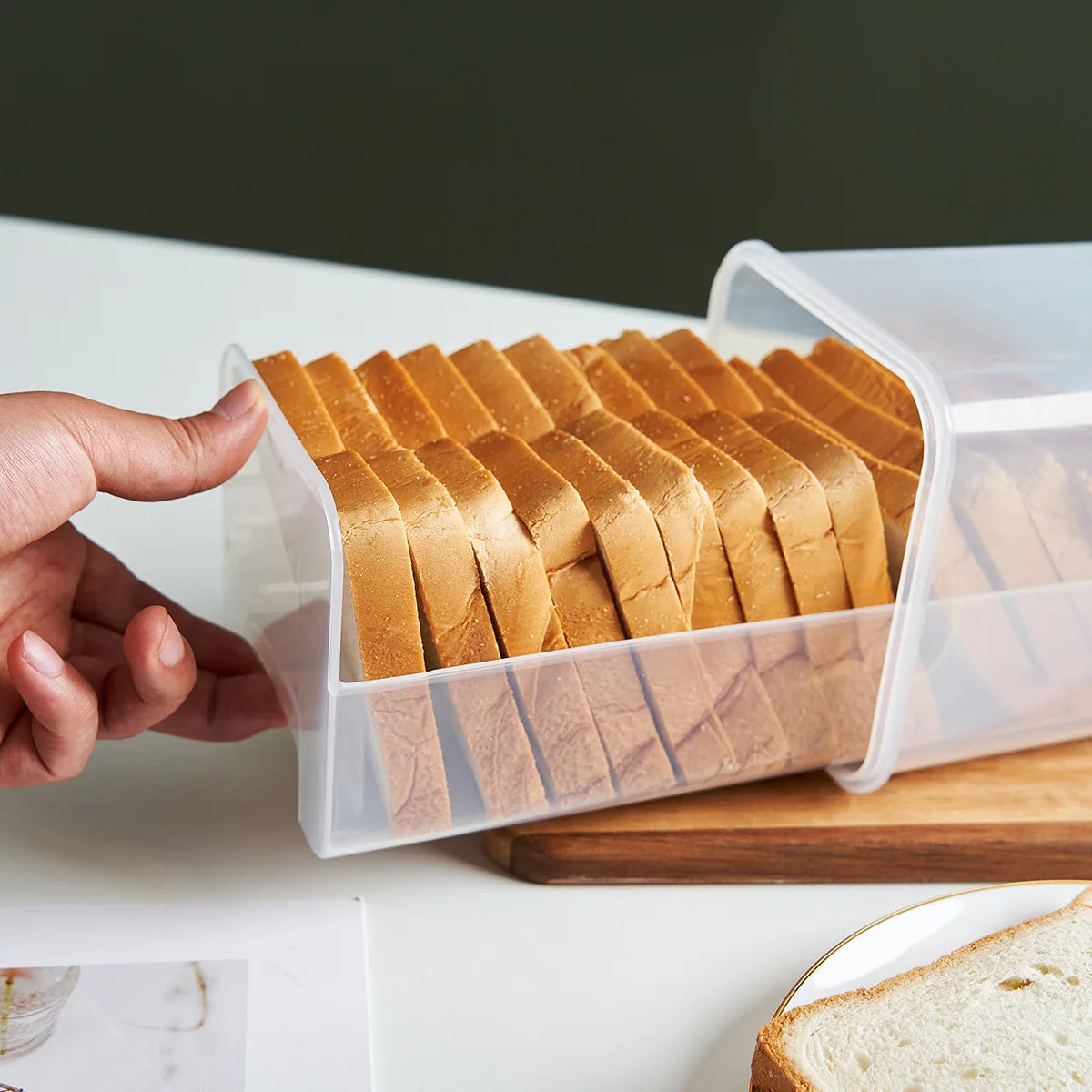 side view of person sliding loaf out from clear rectangular bread box