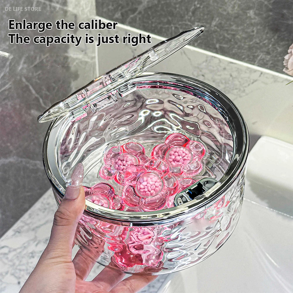 Open clear acrylic storage box with pink laundry pods inside, shown on bathroom counter