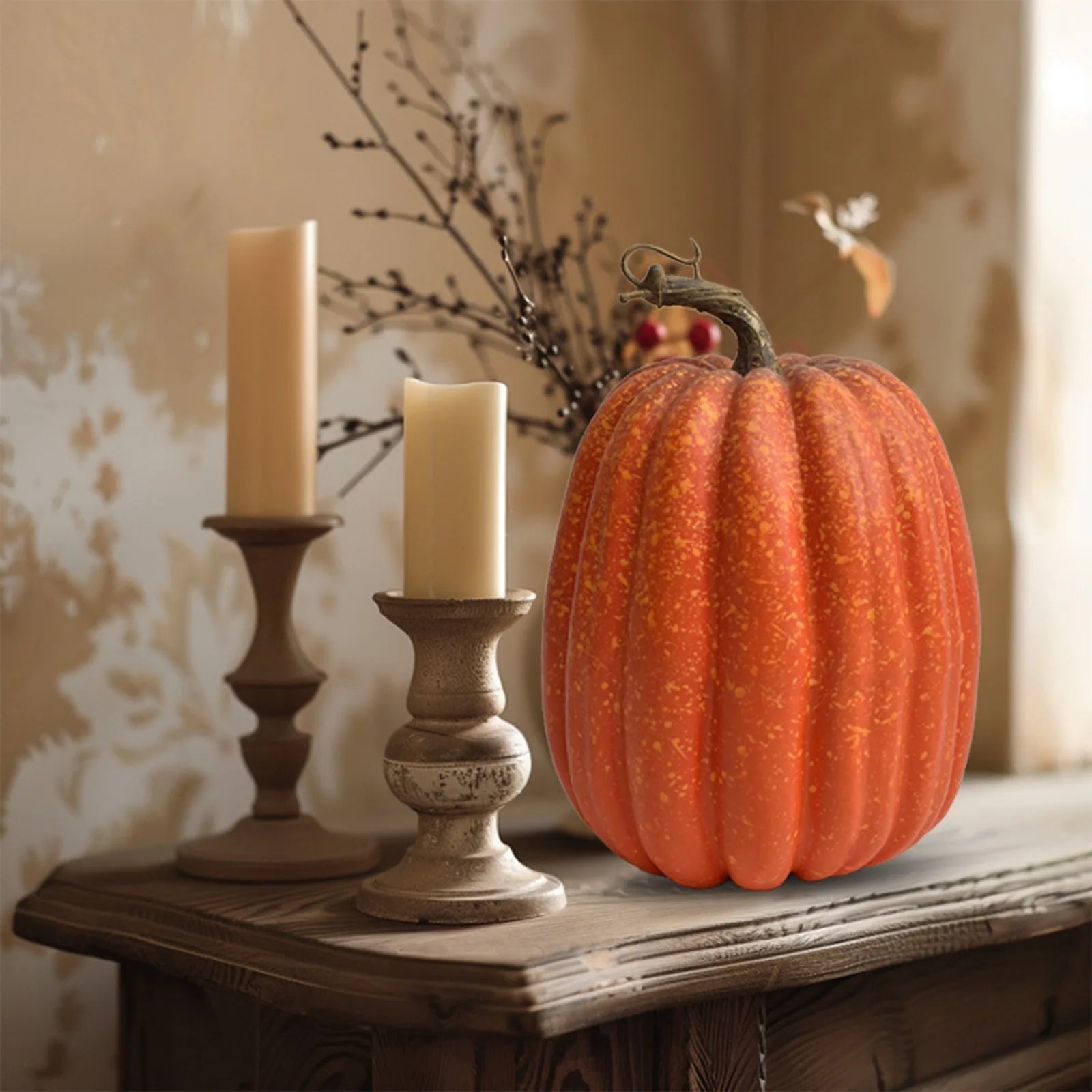 Artificial orange pumpkin on rustic wood table with candlesticks, perfect for autumn centerpieces