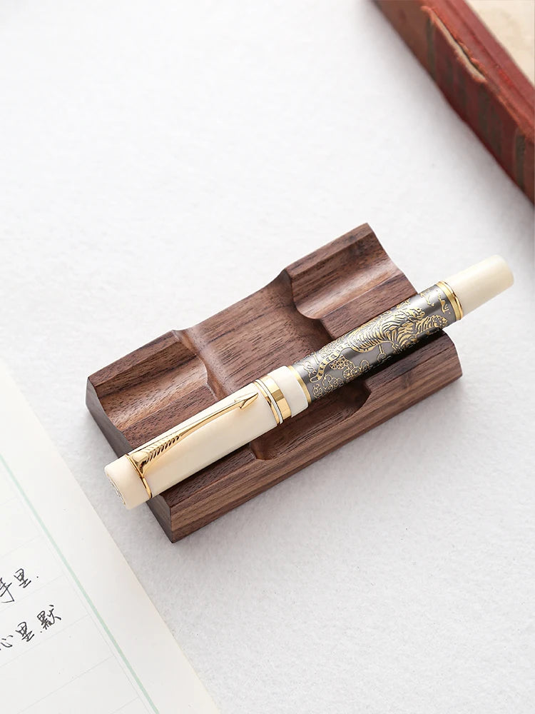 Double pen holder with fountain pen resting in groove on a white desk