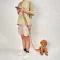Person using a pink hands-free double dog leash to walk a puppy indoors