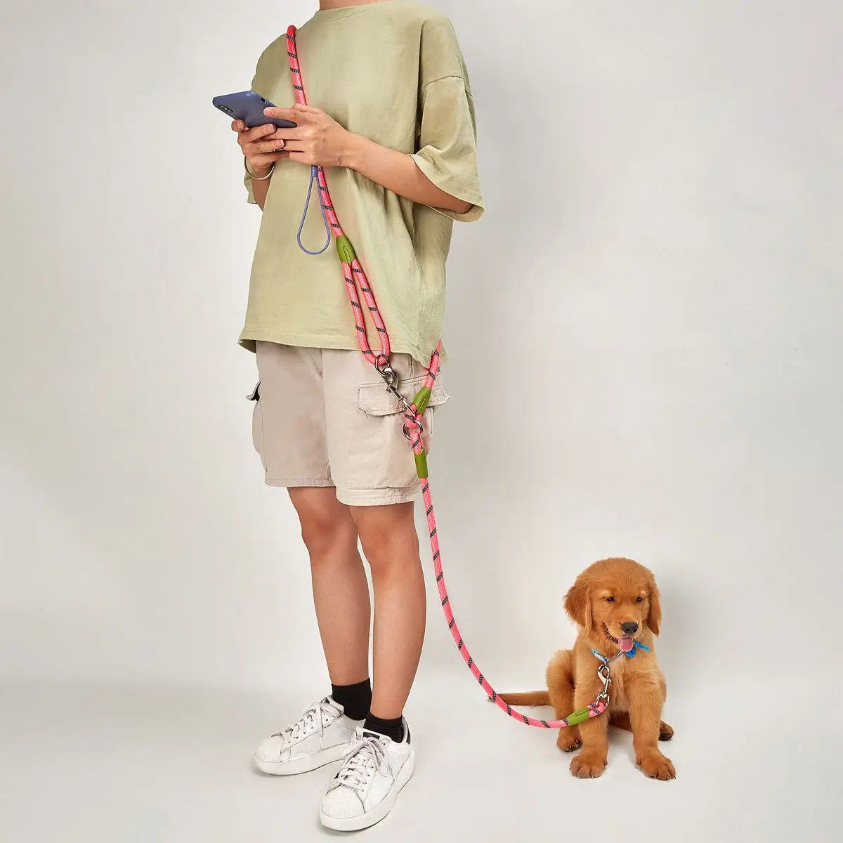 Person using a pink hands-free double dog leash to walk a puppy indoors