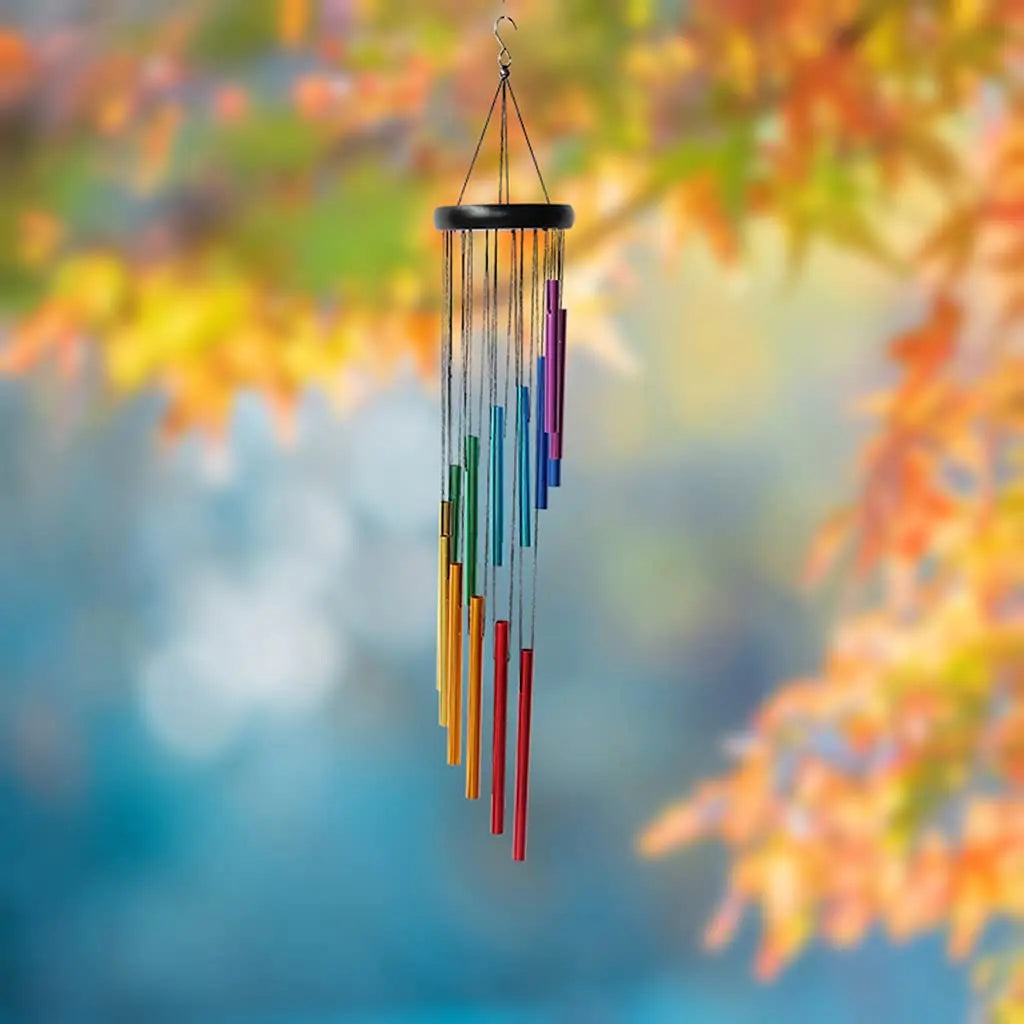 Colorful 12-tube wind chime hanging outdoors with blurred autumn leaves