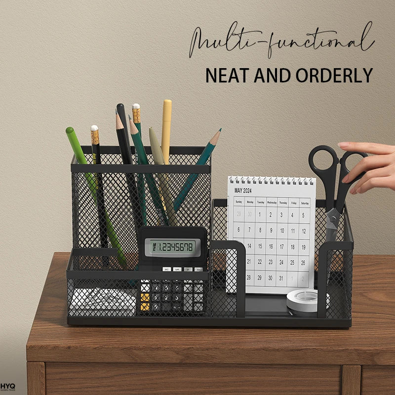 mesh desk organizer with three compartments on a wooden desk, holding pens, calendar, scissors, and calculator