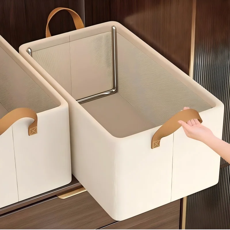 Hand pulling beige canvas stackable storage box with brown handles from a dark wardrobe shelf