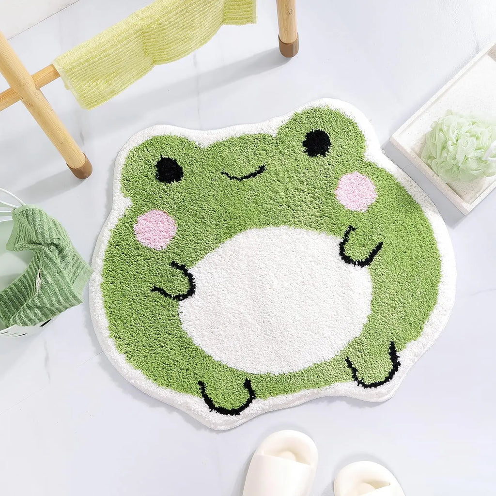 Frog-shaped bathroom mat on tiled floor next to slippers and green washcloth, emphasizing cozy look