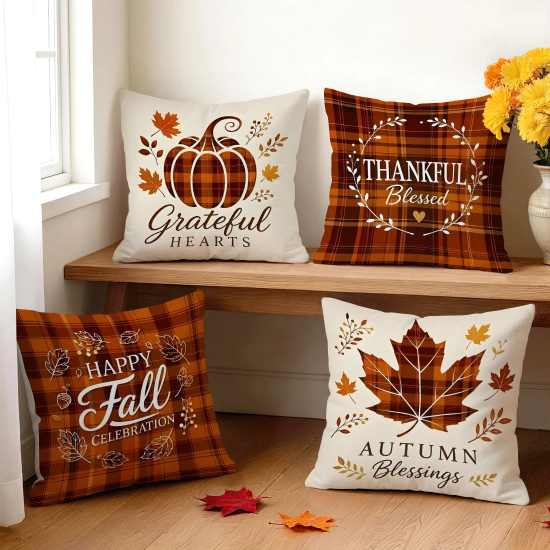 Four autumn-themed pillow covers arranged on a wooden bench beside a window, each cover featuring pumpkin or leaf prints.