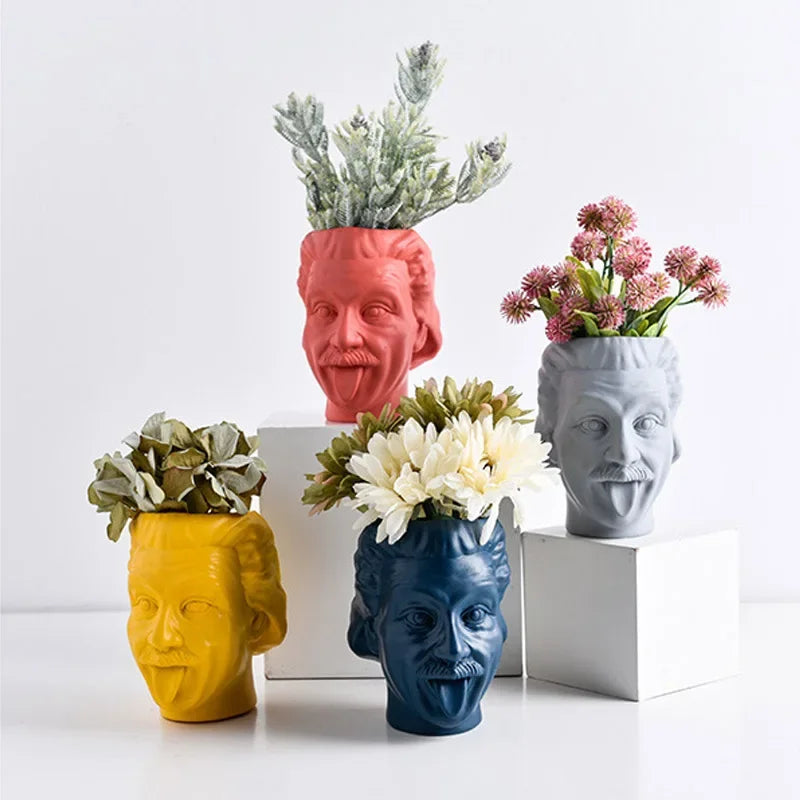Set of four colorful resin head vases in red, yellow, blue, and gray each holding different faux plants