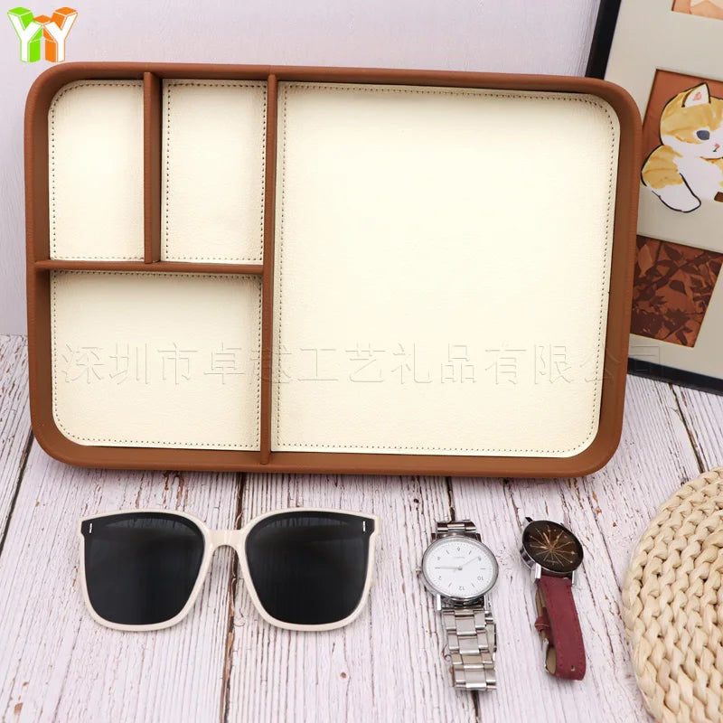 Empty wood organizer tray with cream compartments, shown on a table with accessories nearby