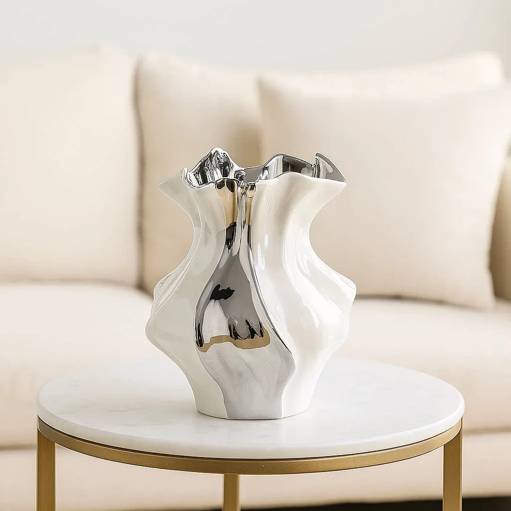silver and white ceramic wave vase on a marble side table with a neutral sofa