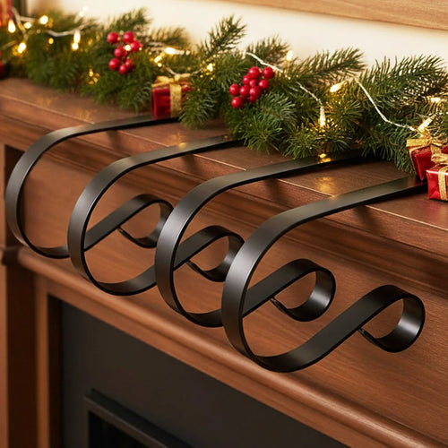 Set of matte black stainless steel stocking holders clipped to a wooden fireplace mantel, holding holiday garland and decorations
