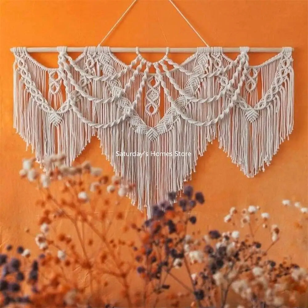 large handwoven macrame wall hanging on orange wall behind dried flowers
