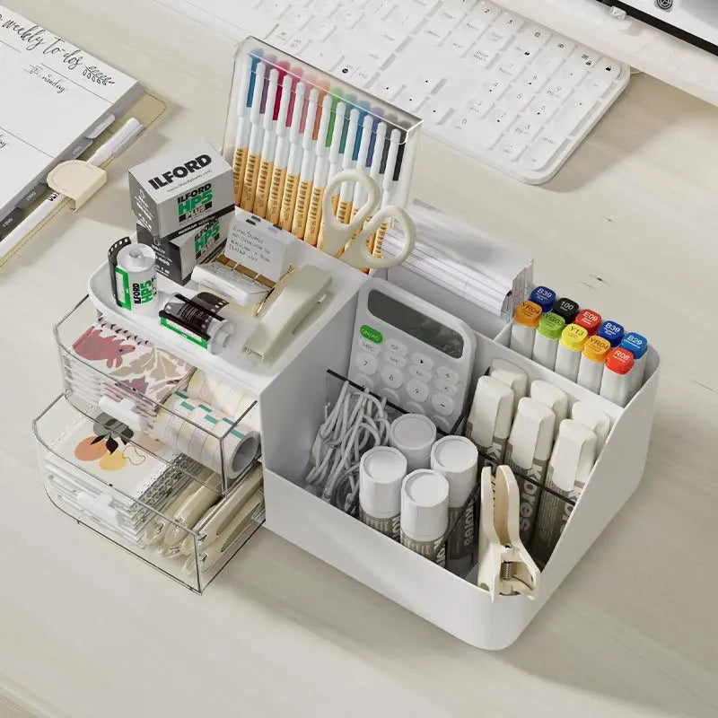 Top-down view of a divided desk storage box holding pens, glue sticks, tape, and paper goods