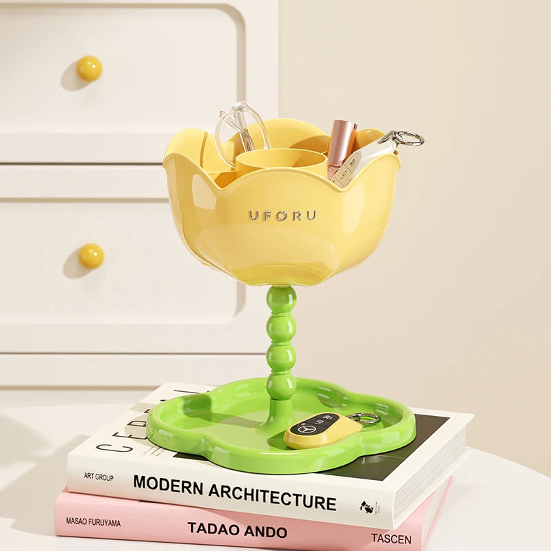 Yellow flower-shaped organizer stand with green tray in use on a white console, holding glasses and small items
