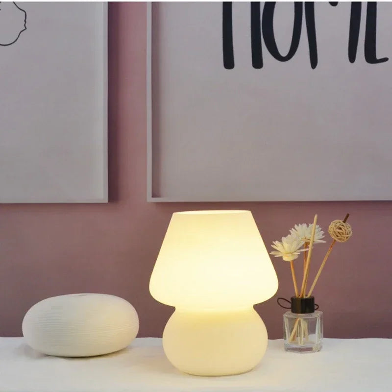 Lit glass mushroom table lamp on nightstand with simple decor accents
