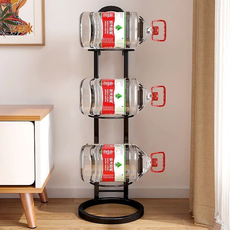 Three-tier black metal rack shown holding large water bottles, set in a bright room next to a window and a low sideboard.