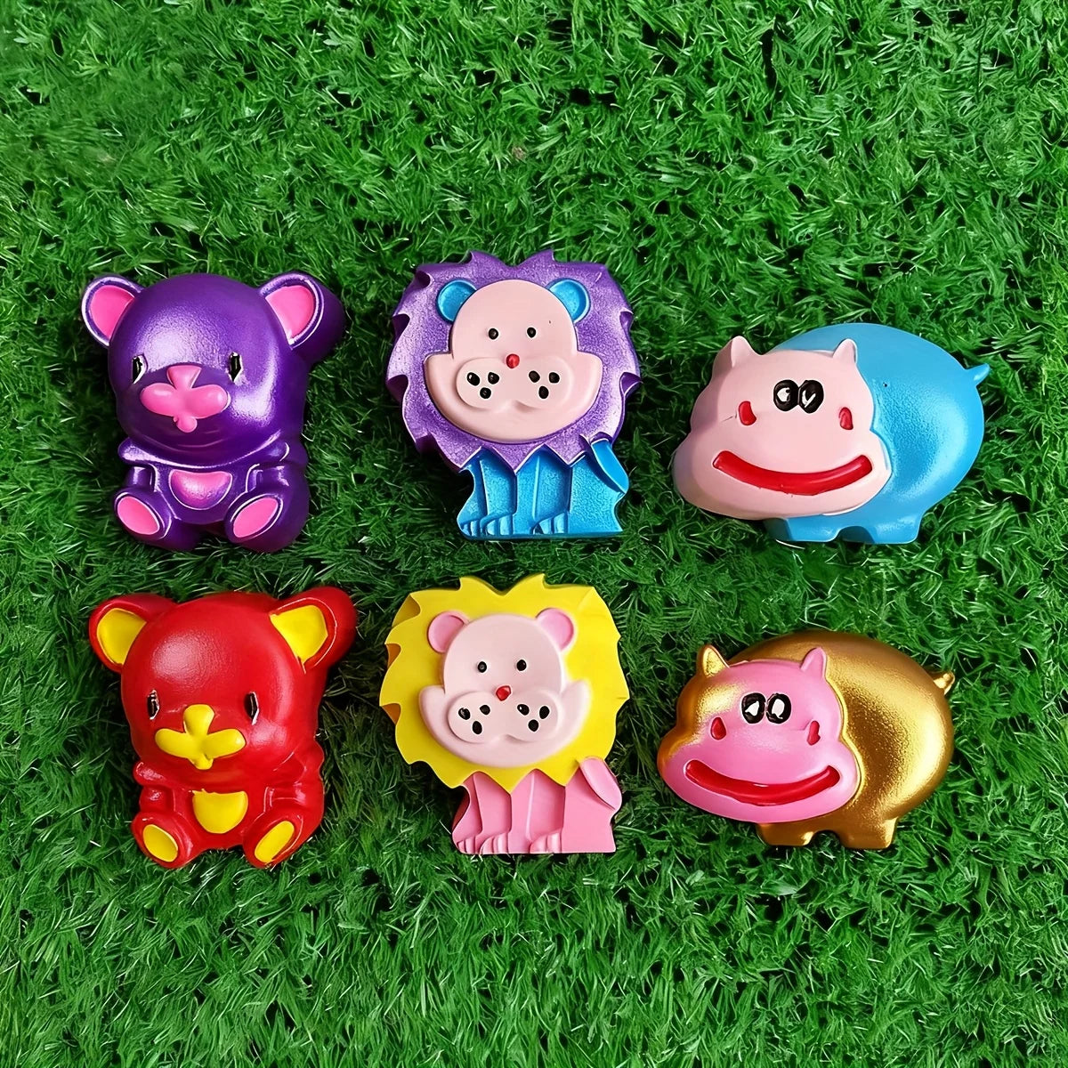 Set of six brightly painted animal soaps including bear, lion, and hippo, on green grass background