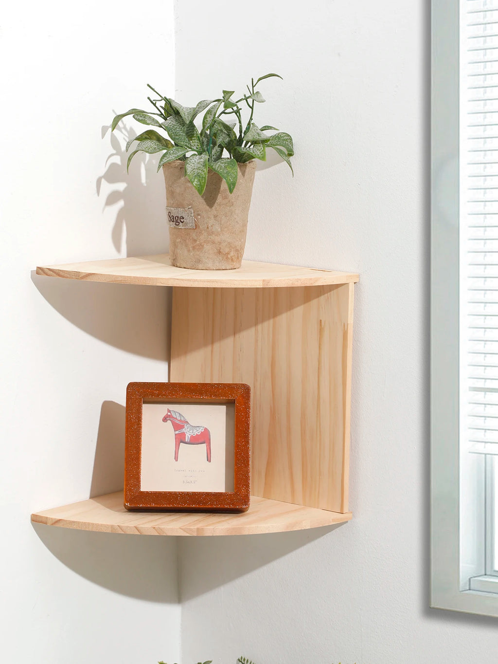 close view of wooden corner shelf with plant and frame on wall