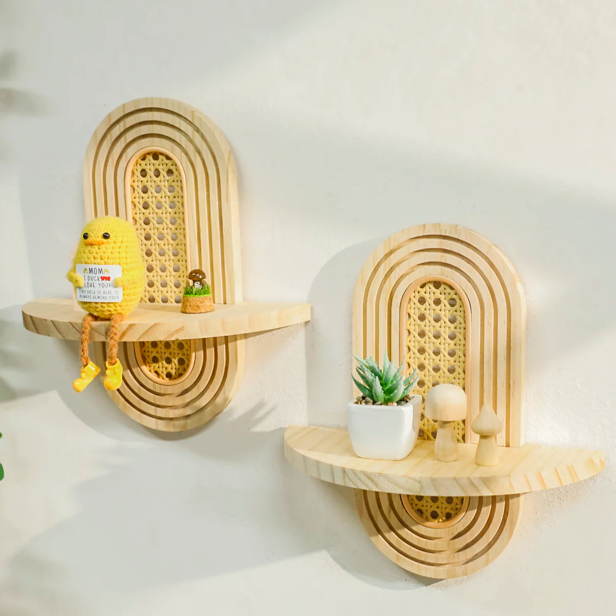 side view of arched rattan-inlay wall shelves displaying a knit figure, small plant, and mushrooms