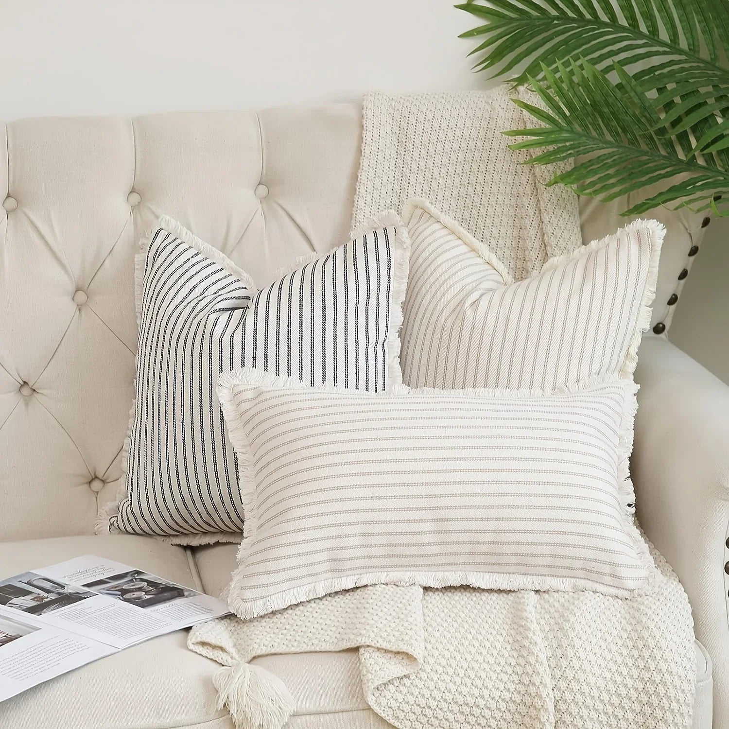 Striped throw pillow covers on neutral tufted sofa with cozy knitted throw