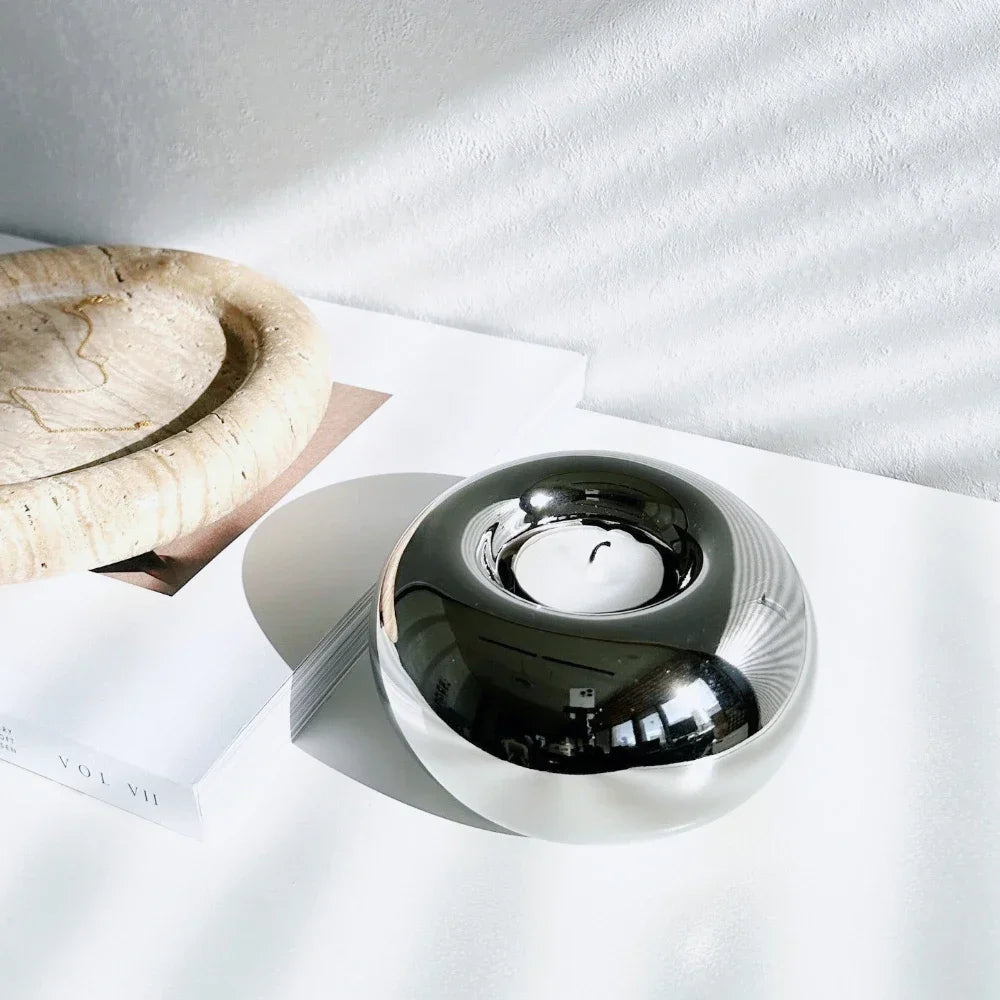 reflective silvery ceramic tealight holder with unlit tealight on a white surface