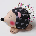 Cartoon hedgehog-shaped pin cushion holding colorful sewing pins