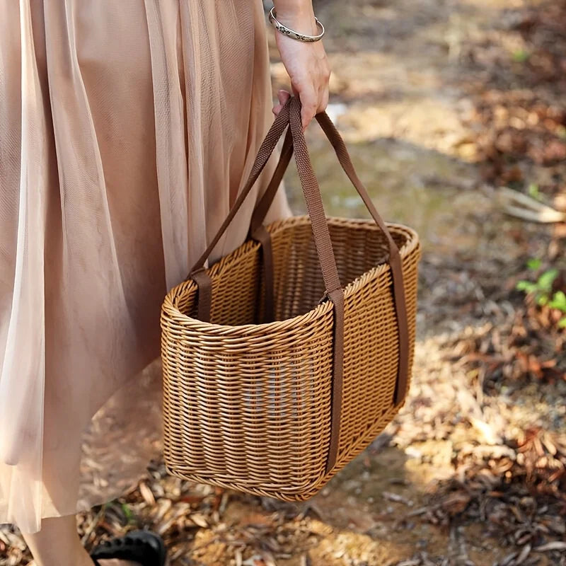Woman carrying handwoven chocolate brown rattan storage basket tote outdoors