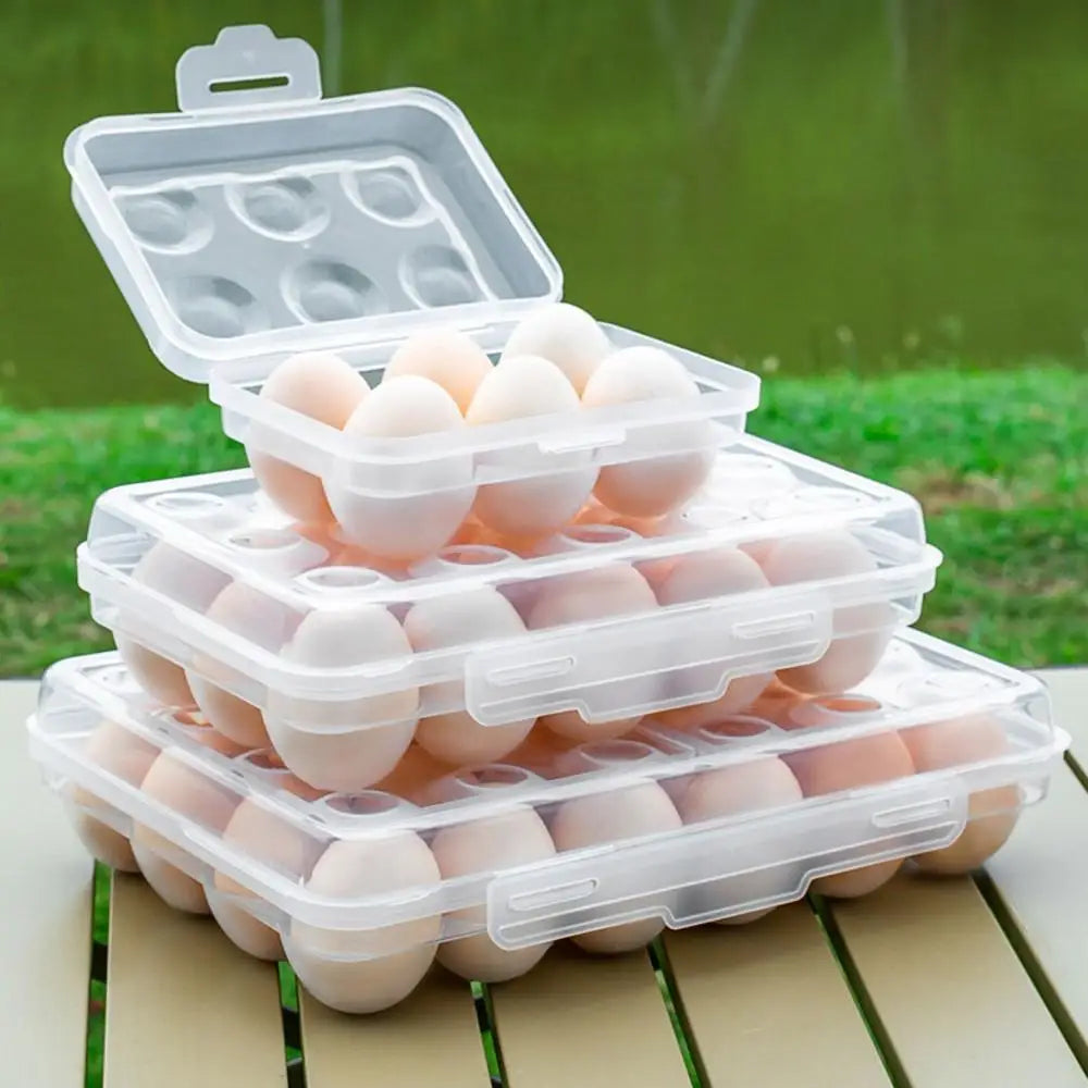 three stackable plastic egg holders with lids holding brown eggs, placed on a table outdoors
