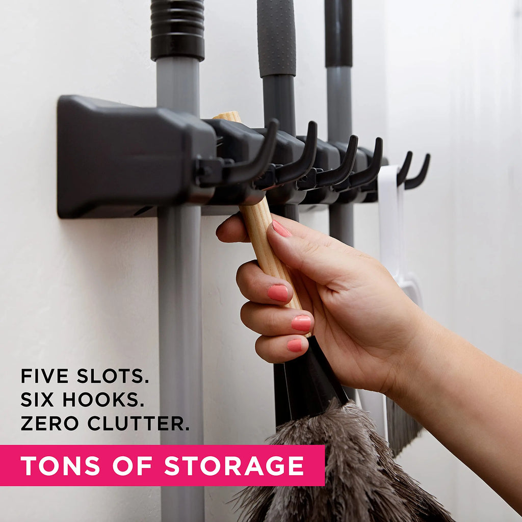 Hand inserting cleaning tool into black wall-mounted rack with five slots and six hooks