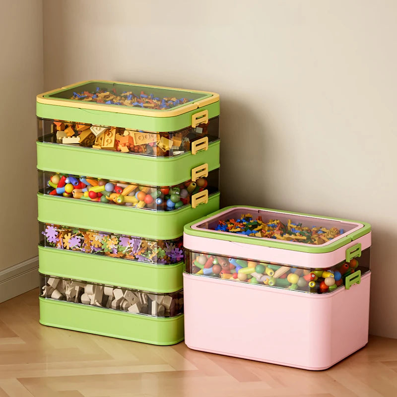 Stackable plastic storage boxes with handle and clear sides, filled with toys and blocks, shown in green and pink colors set in a corner