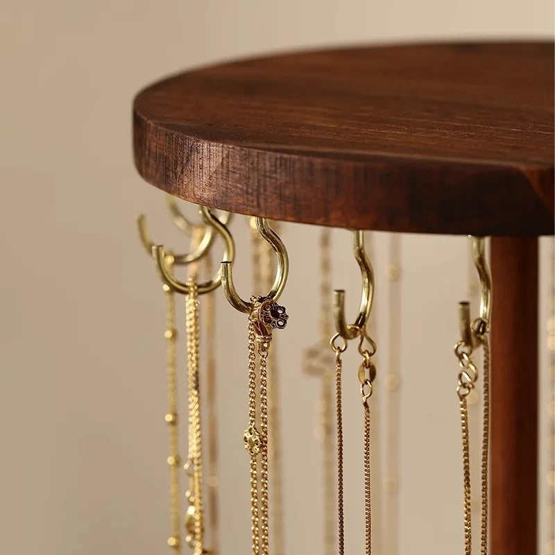Close-up of gold hooks on round walnut wood necklace stand top