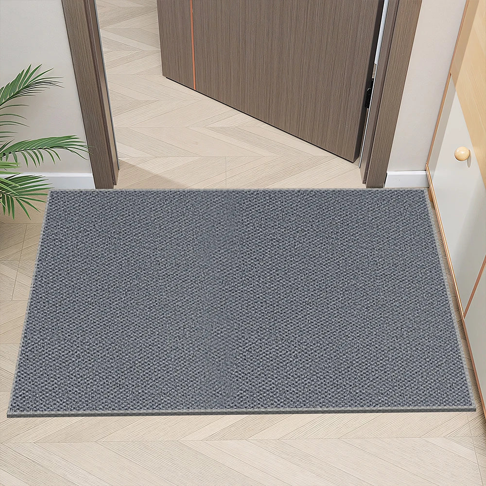 neutral gray textured doormat placed at a home entryway with herringbone wood flooring