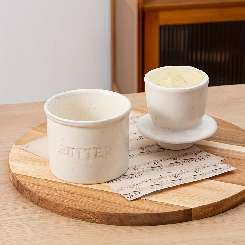 Speckled white ceramic French butter crock with lid, open, on a wooden board