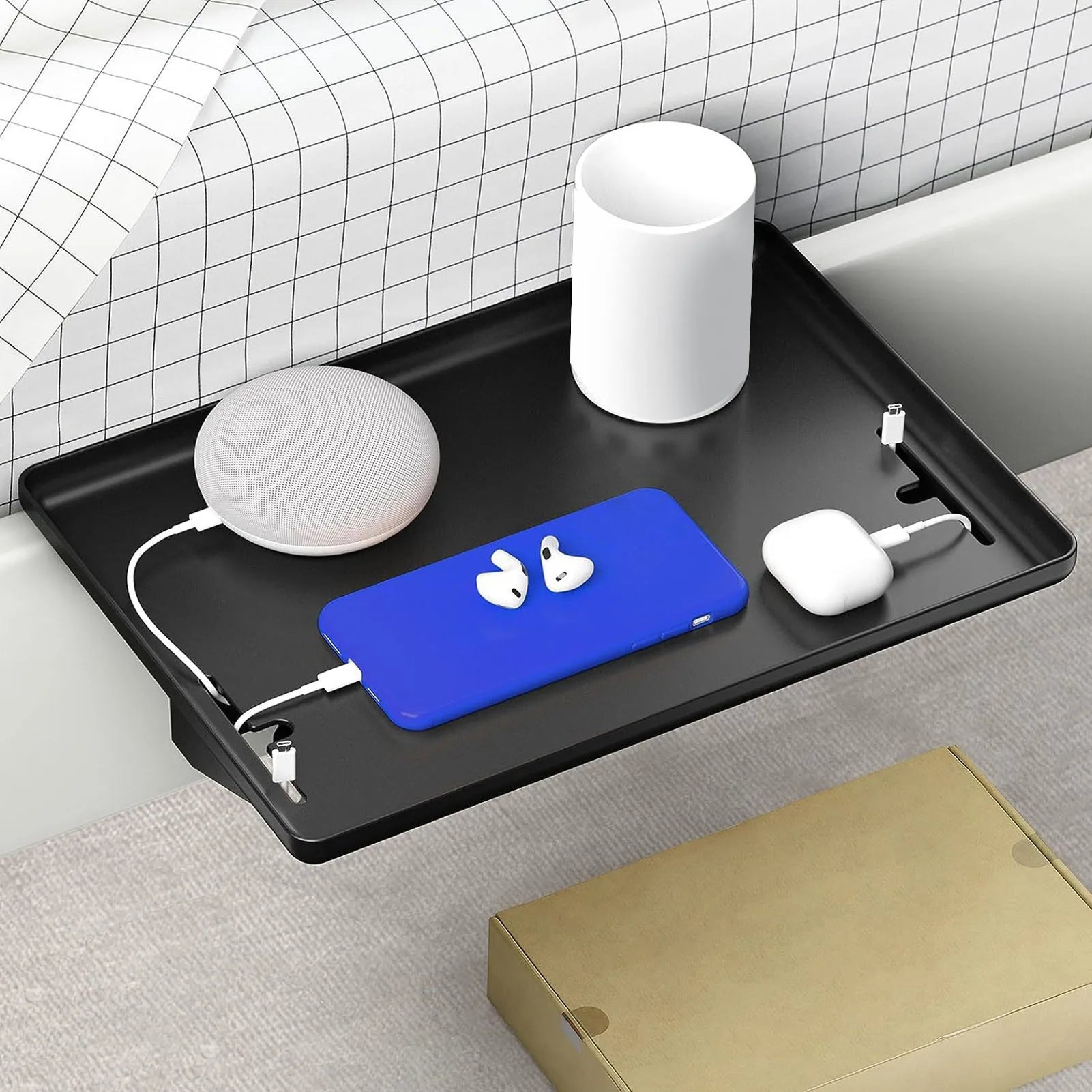 Clamp-on black ABS bedside shelf attached to bed rail, holding phone, cup, and small tech items