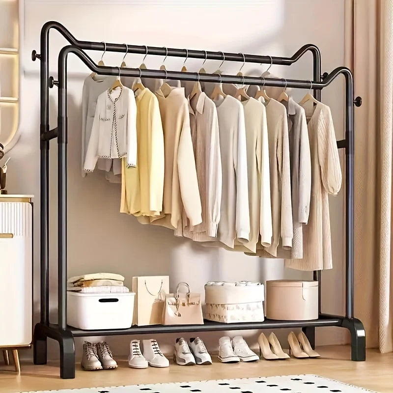 Black twin bar clothes rack with two hanging rails and a shoe shelf organized with clothes, bags, and shoes in a bedroom setting