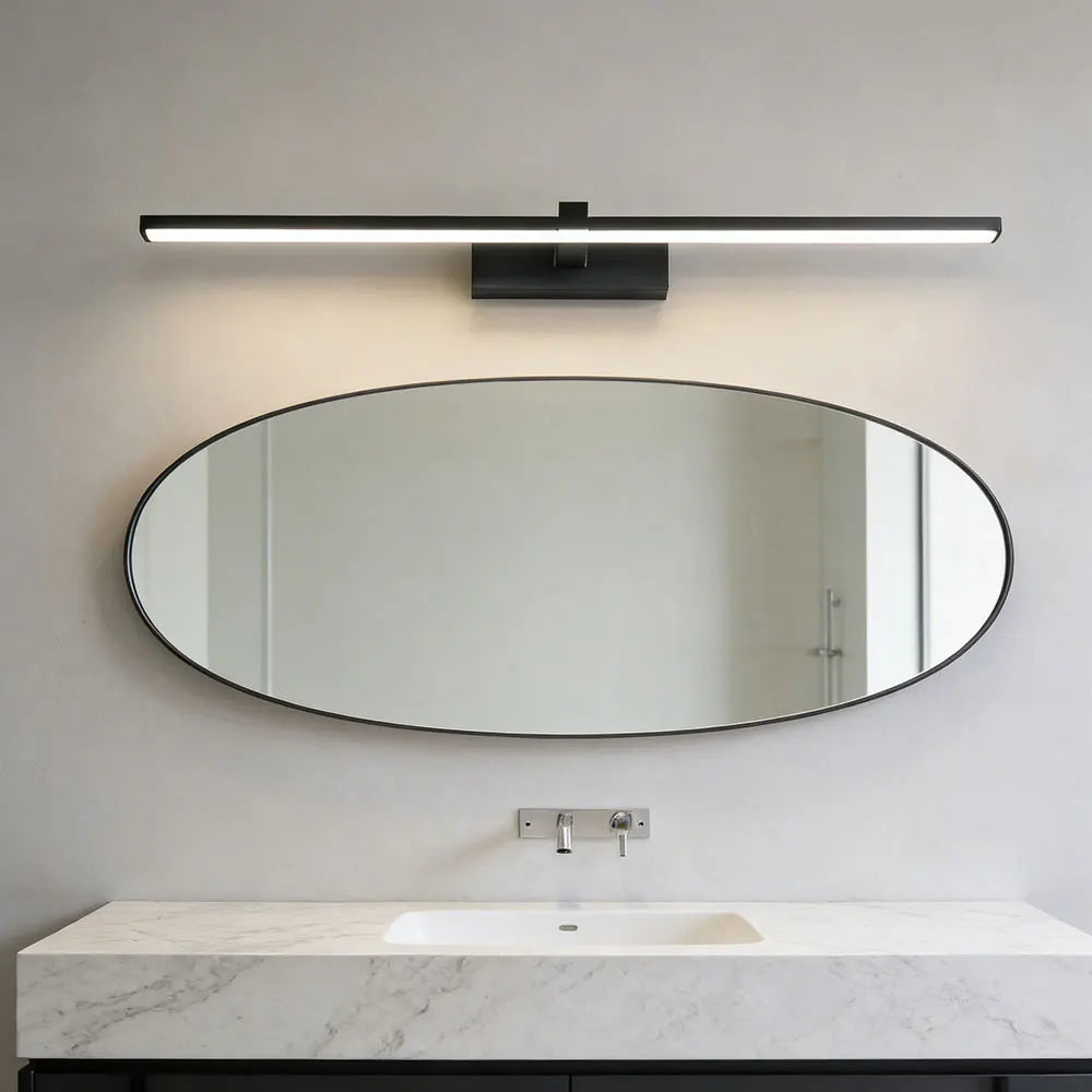 Black LED wall sconce above oval bathroom mirror with marble countertop