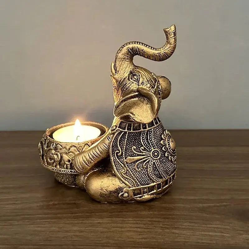 Close-up of a gold elephant resin tealight candle holder with lit candle on a wooden surface.