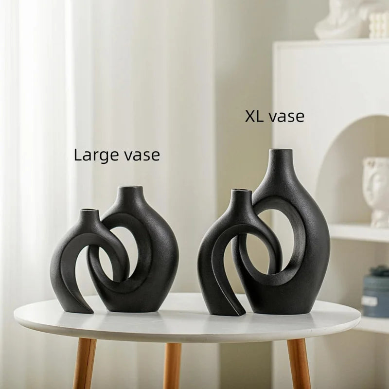 black sculptural resin vases labeled large and XL on a round white table