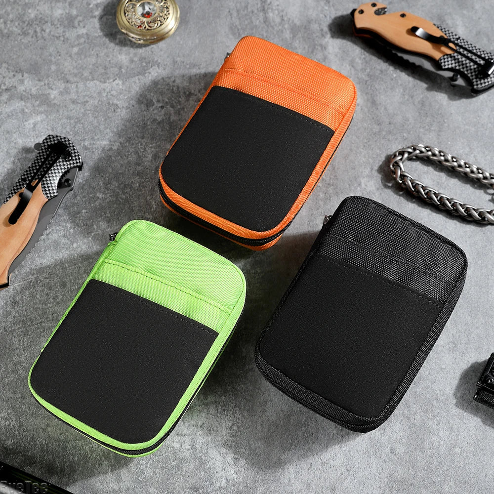 Three compact utility organizer pouches in orange, green, and black on a gray surface, surrounded by small tools.