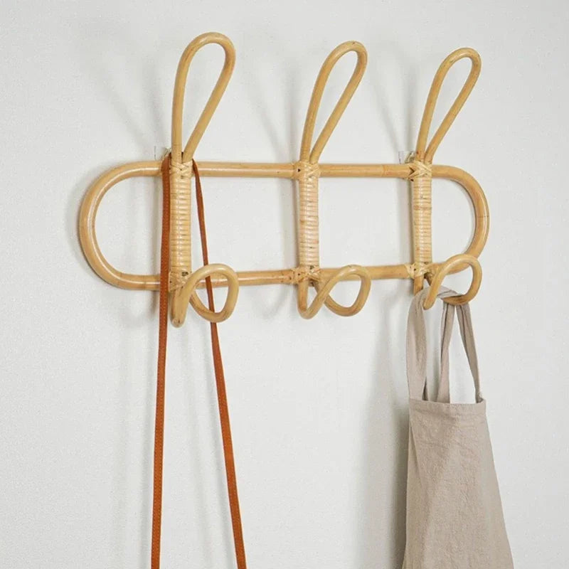 Three-hook rattan wall rack mounted on white wall with bags hanging from hooks