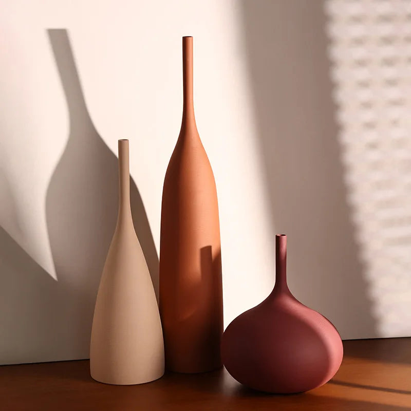 Set of handmade ceramic vases in warm neutral and rust colors in sunlight on a table