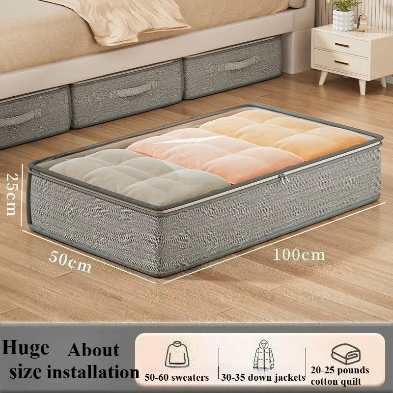 Large gray fabric under-bed storage bin under a bed, size labeled 100x50x25 cm, filled with bedding
