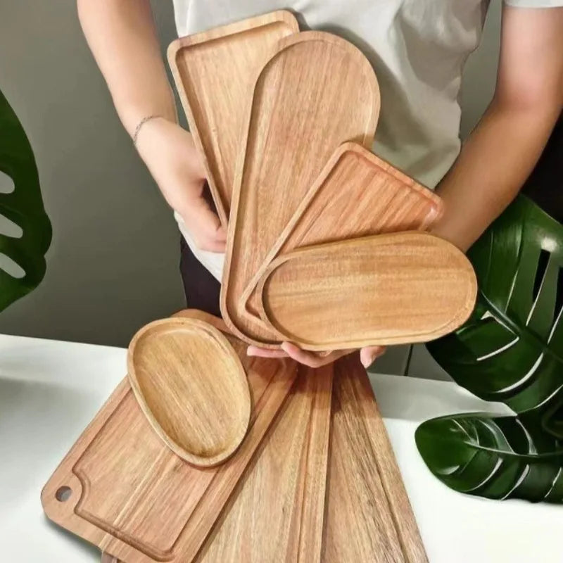 Person holding assorted oval and rectangular acacia wood trays to show shapes and natural wood grain