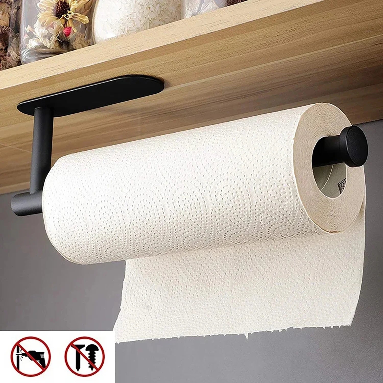 Black adhesive paper towel holder mounted under a kitchen cabinet with a paper towel roll