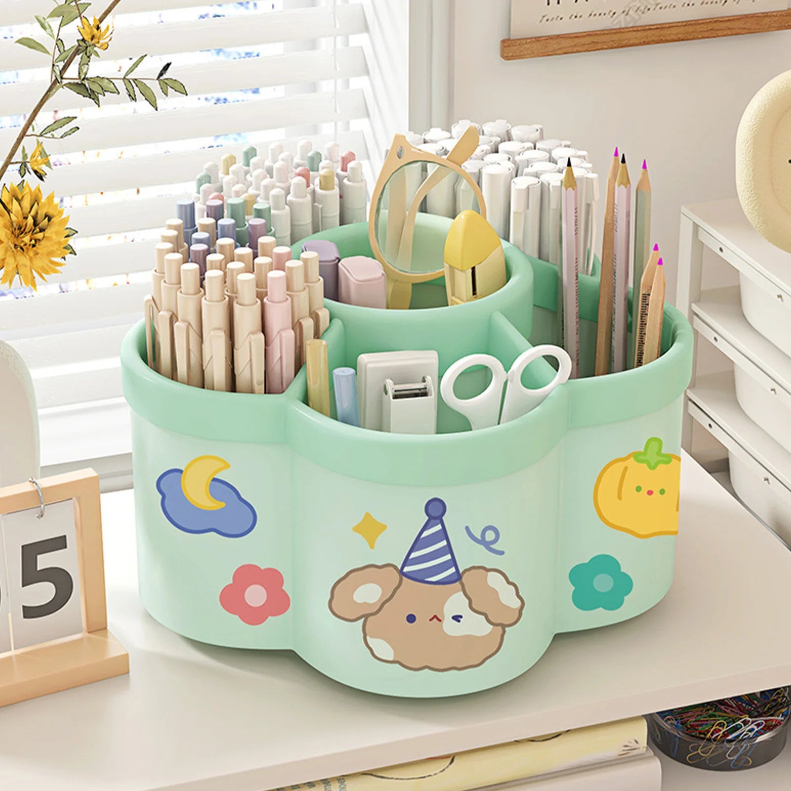 Green kawaii rotating desk organizer holding pens, pencils, and scissors on a study table
