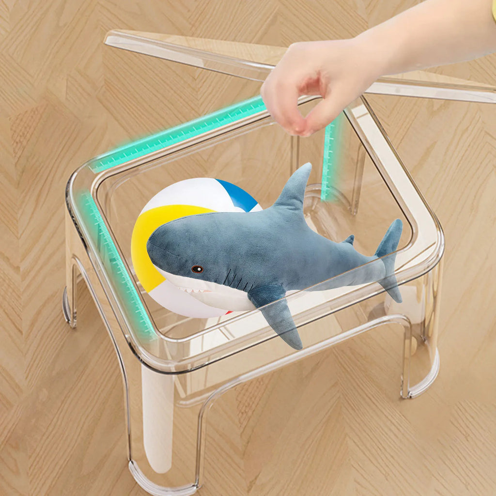 Hand placing plush toys inside the clear storage step stool's inner compartment