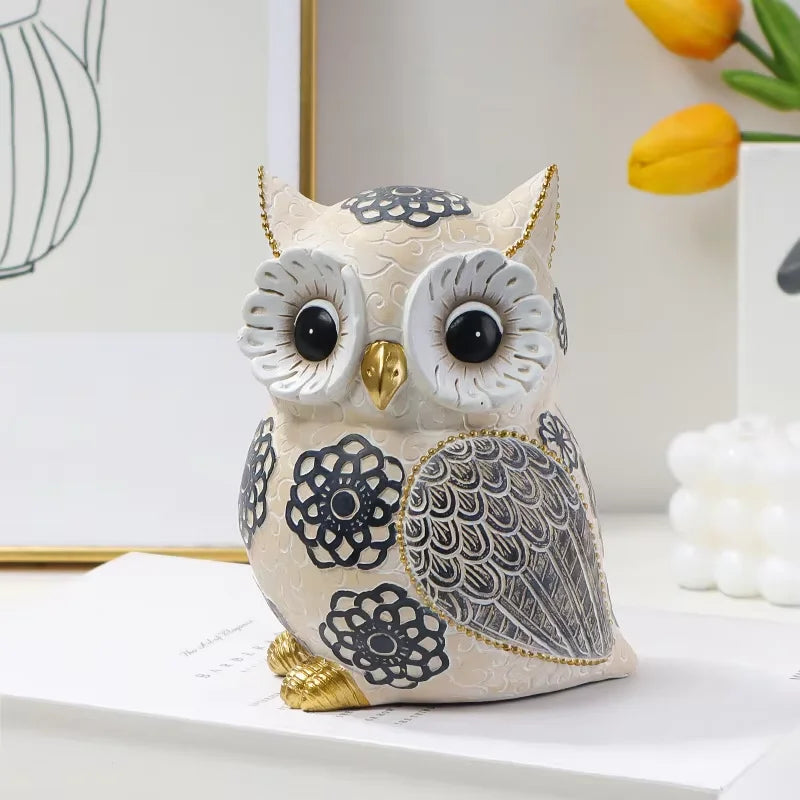 front view of whimsical resin owl sculpture with gold beak and feet on a bright shelf